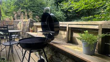 Una parrilla para barbacoa al aire libre con una terraza de madera y sillas.