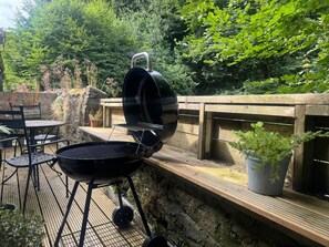 Una parrilla para barbacoa al aire libre con una terraza de madera y sillas.