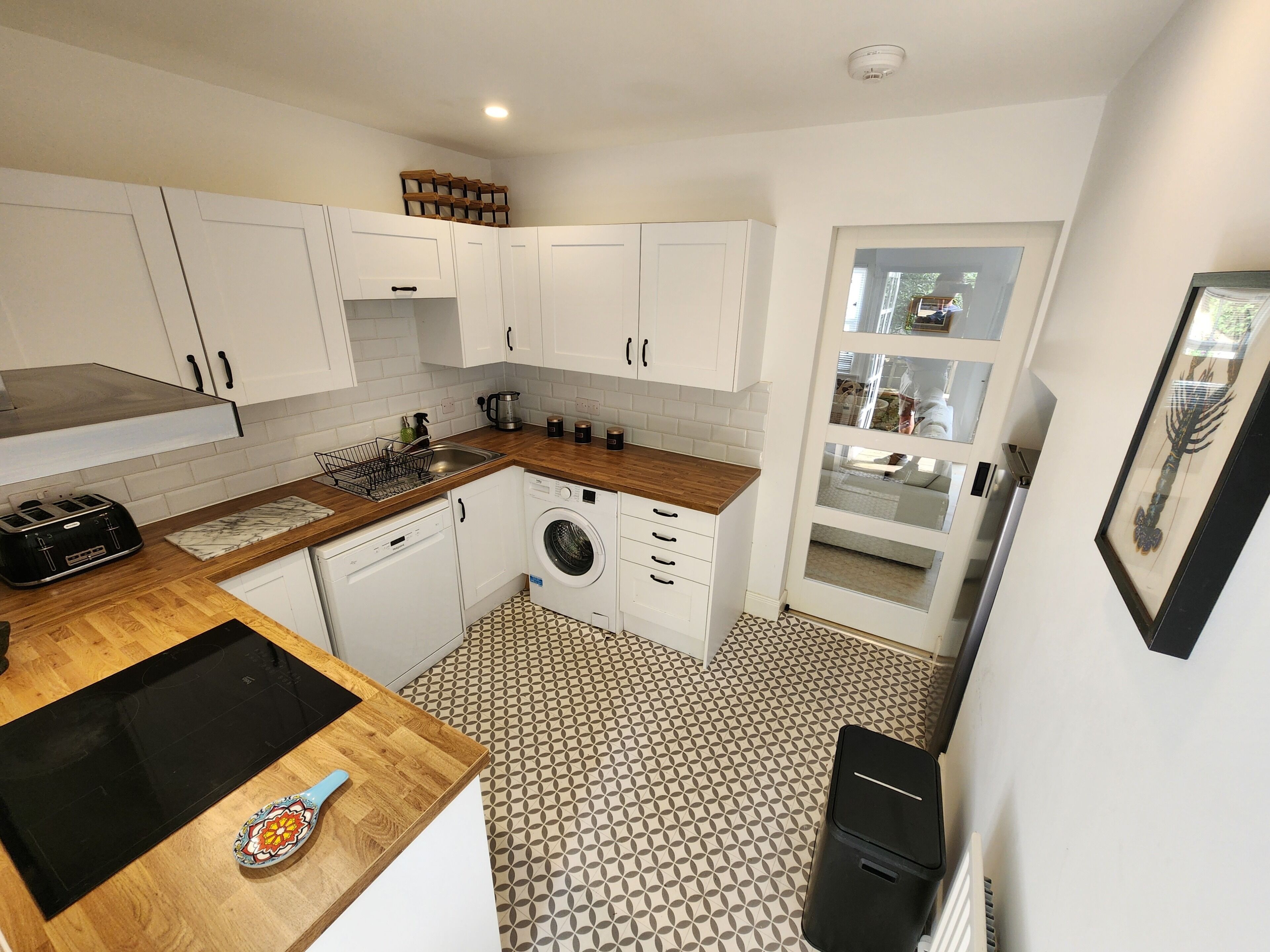 Une cuisine de taille réduite avec des meubles blancs, un plan de travail en bois, un lave-linge et un évier.