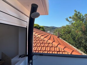 Ein Dach mit Terrakotta-Ziegeln und freiem Blick auf die umliegende Landschaft.