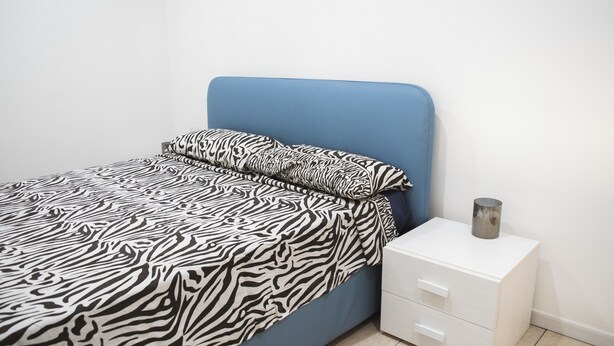 A bedroom with a bed, a nightstand, and a drawer unit. - Huge Terrace Sea Front (Bosa Marina)