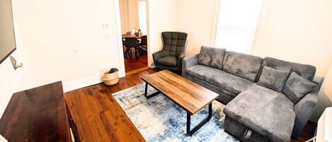 A living room with a sofa, a coffee table, and a television.