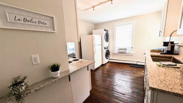 Una cocina con mostrador, refrigerador, lavadora y ventana.