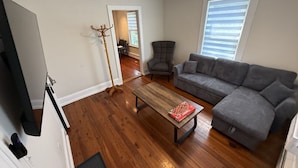 Una sala de estar con un sofá gris, una mesa de centro de madera y un perchero.