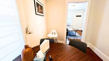 A conference room with a wooden table, chairs, a vase, a tissue box, and a water bottle.