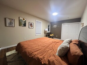 Ein Schlafzimmer mit einem Bett, einer Tür und einem an der Wand befestigten Regal.