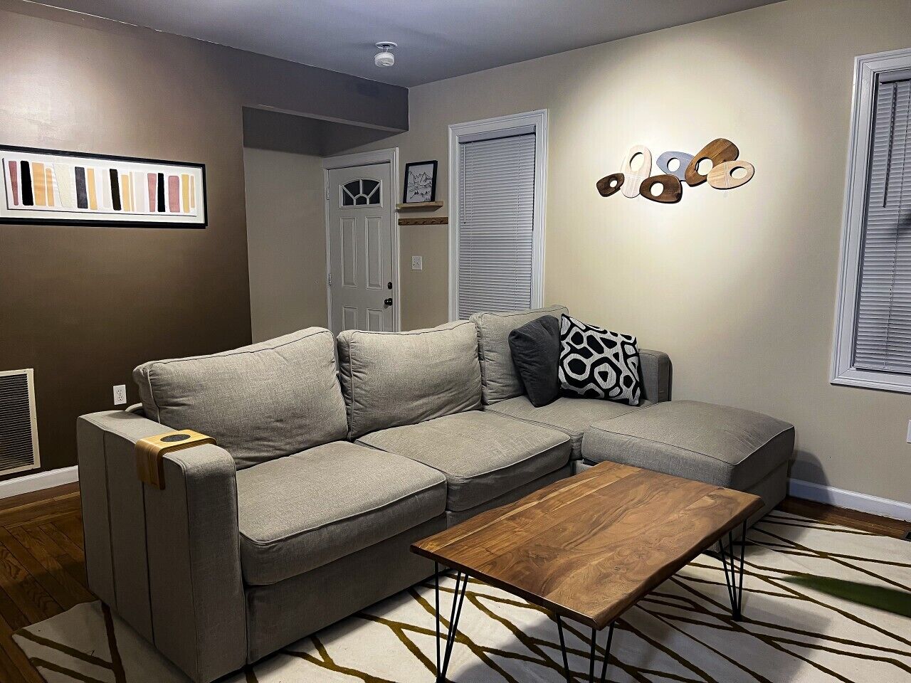 A living room with a grey sectional sofa, a wooden coffee table, and a patterned rug.