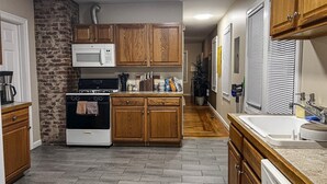 A kitchen with wooden cabinets, a microwave, a stove, and a sink. - Quiet 1st-Floor 2BR Haven w/ King Bed, Desks, In-Unit Laundry & 2-Car Parking | Walk to Yale (New Haven)