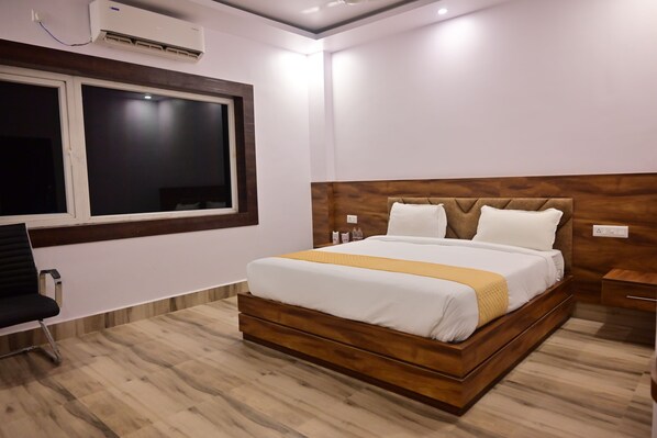 A hotel room with a large bed, a window, a desk, and a chair.