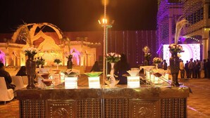 Un espacio decorado para un evento, con una mesa central, arreglos florales y un fondo iluminado.