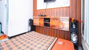 A bedroom with a bed, a mounted TV, a wooden panel wall, and a window. - Cozzy Villa Azzalia (batu)