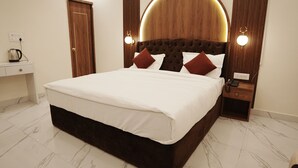 A modern hotel room with a large bed, a wooden headboard, bedside lamps, a nightstand, and a marble-tiled floor. - VENUS INN ROOMS  AND BANQUETS (Lucknow)