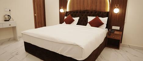 A modern hotel room with a large bed, a wooden headboard, bedside lamps, a nightstand, and a marble-tiled floor.