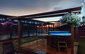 An outdoor deck with a hot tub, wooden pergola, and string lights. - Nice home in Darlowo with sauna (Darlowo)