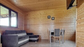 Ein Ferienhaus-Innenraum mit einer Couch, einem Esstisch mit Stühlen und Holzwänden.