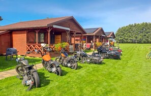 A row of motorbikes parked in front of a wooden building with a porch. - Nice home in Darlowo with sauna (Darlowo)