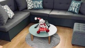 Un soggiorno moderno con un divano grigio, un tavolino rotondo e un orsacchiotto.