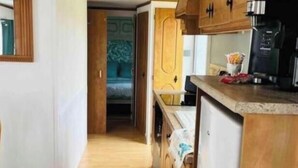 Una cucina compatta con mobili in legno, un frigorifero e una macchina da caffè.