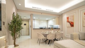 Uma sala de estar moderna com área de jantar, um sofá, uma mesa de centro e uma planta decorativa.