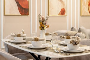 A dining area with a table set for four, including bowls, plates, cutlery, and glasses. - Luxury 2BR Paramount Infinity Pool  (Dubai)