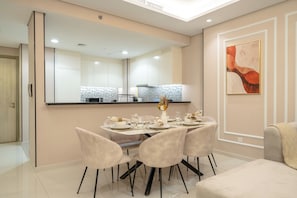 Uma área de jantar moderna com um espelho grande, uma mesa de jantar posta para quatro pessoas e uma obra de arte contemporânea na parede.