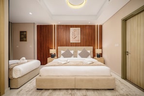 Quarto de hotel com uma cama grande, duas mesas de cabeceira, cabeceira com design de folha e uma luminária de teto circular.