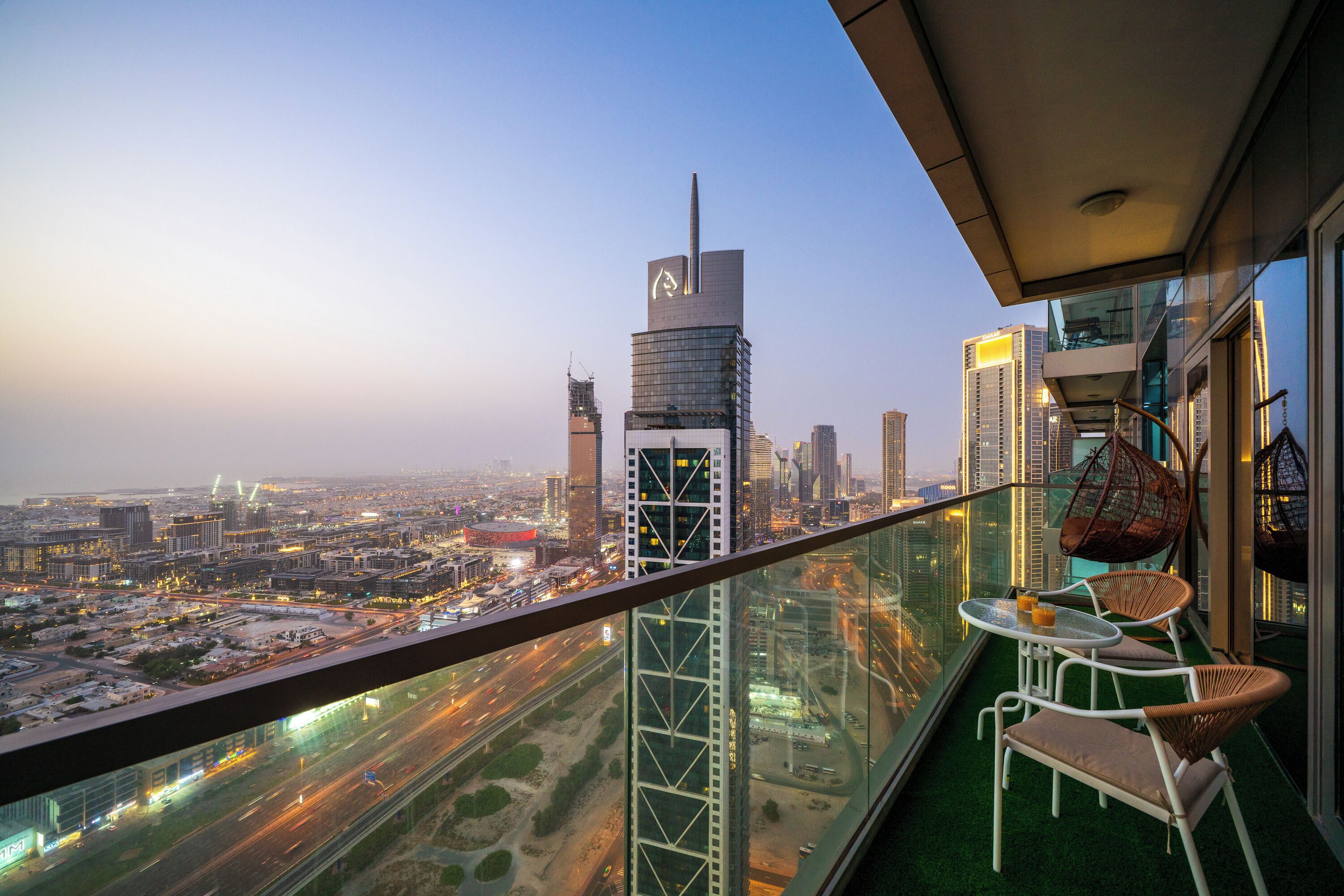 A high-rise building with a glass balcony overlooking a cityscape at dusk.
