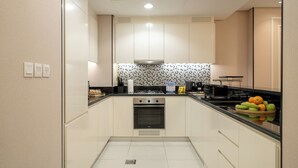 Uma cozinha moderna com armários brancos, bancada preta e painel de azulejos.