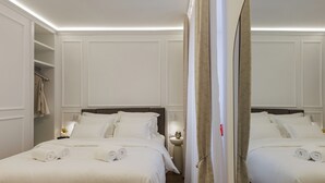 Een hotelkamer met twee bedden, een kledingkast, een nachtkastje met een lamp en een spiegel.