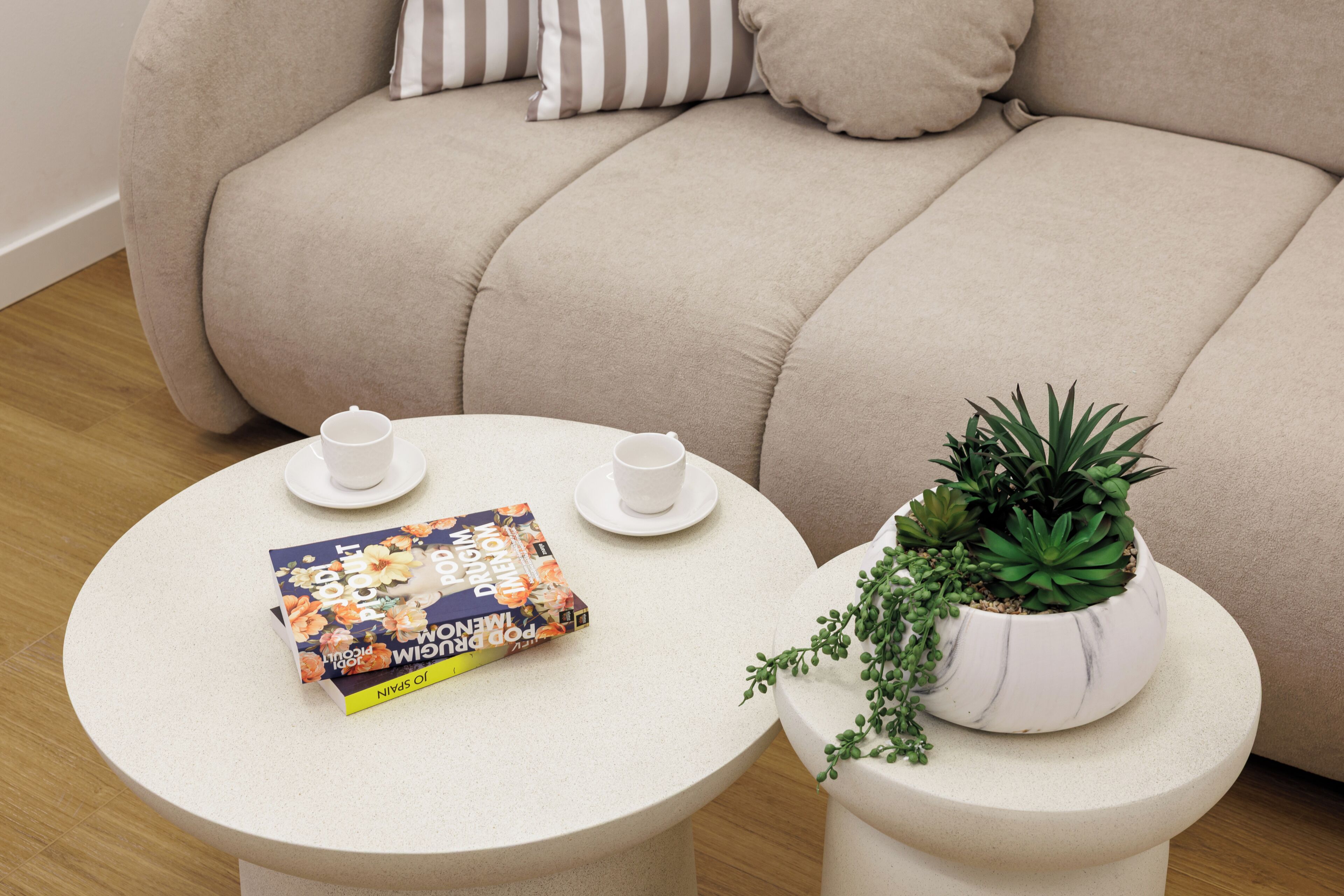 A round table with a book, two cups, and a potted plant.