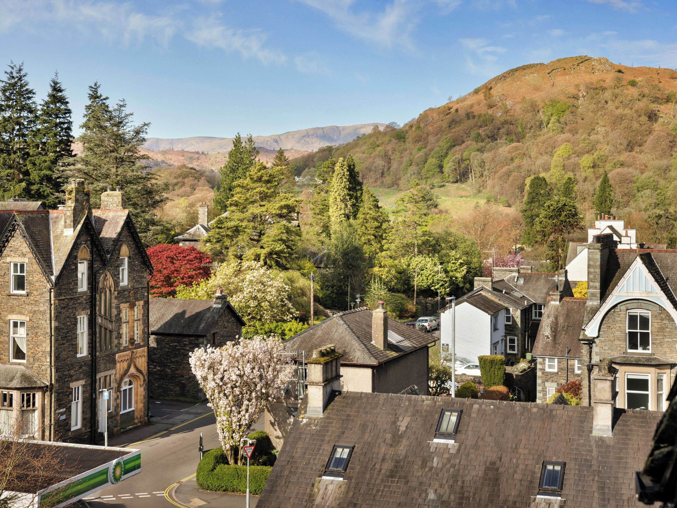 A residential area with stone buildings, a clear sky, and a hill in the background.