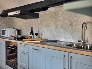 A kitchen with a microwave, wine bottle, rolling pin, and a book on the counter. - 0 bedroom accommodation in Ambleside (Ambleside)
