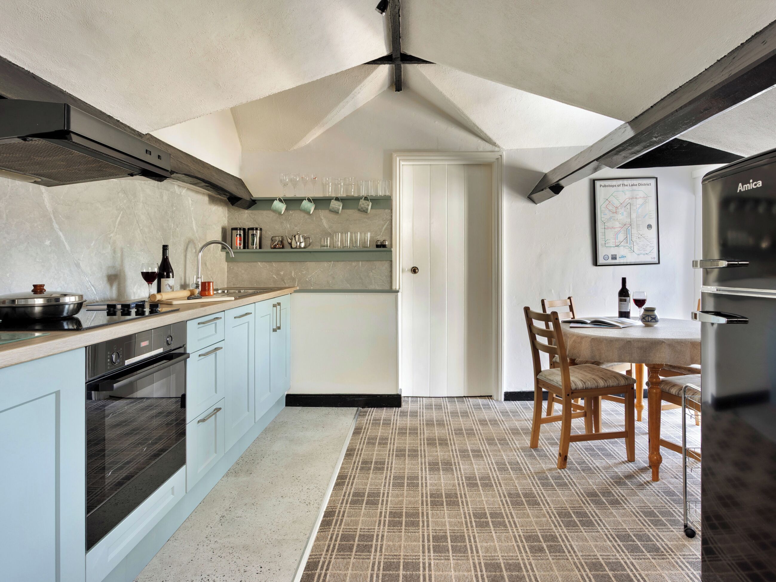 A modern kitchen with light blue cabinets, a black stove, and a dining area with a table and chairs.