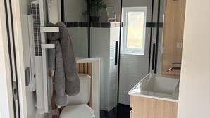 A modern bathroom with a toilet, sink, and shower area. - Equi Lodge Jacuzzi in the heart of the forest near Disney (La Houssaye-en-Brie)