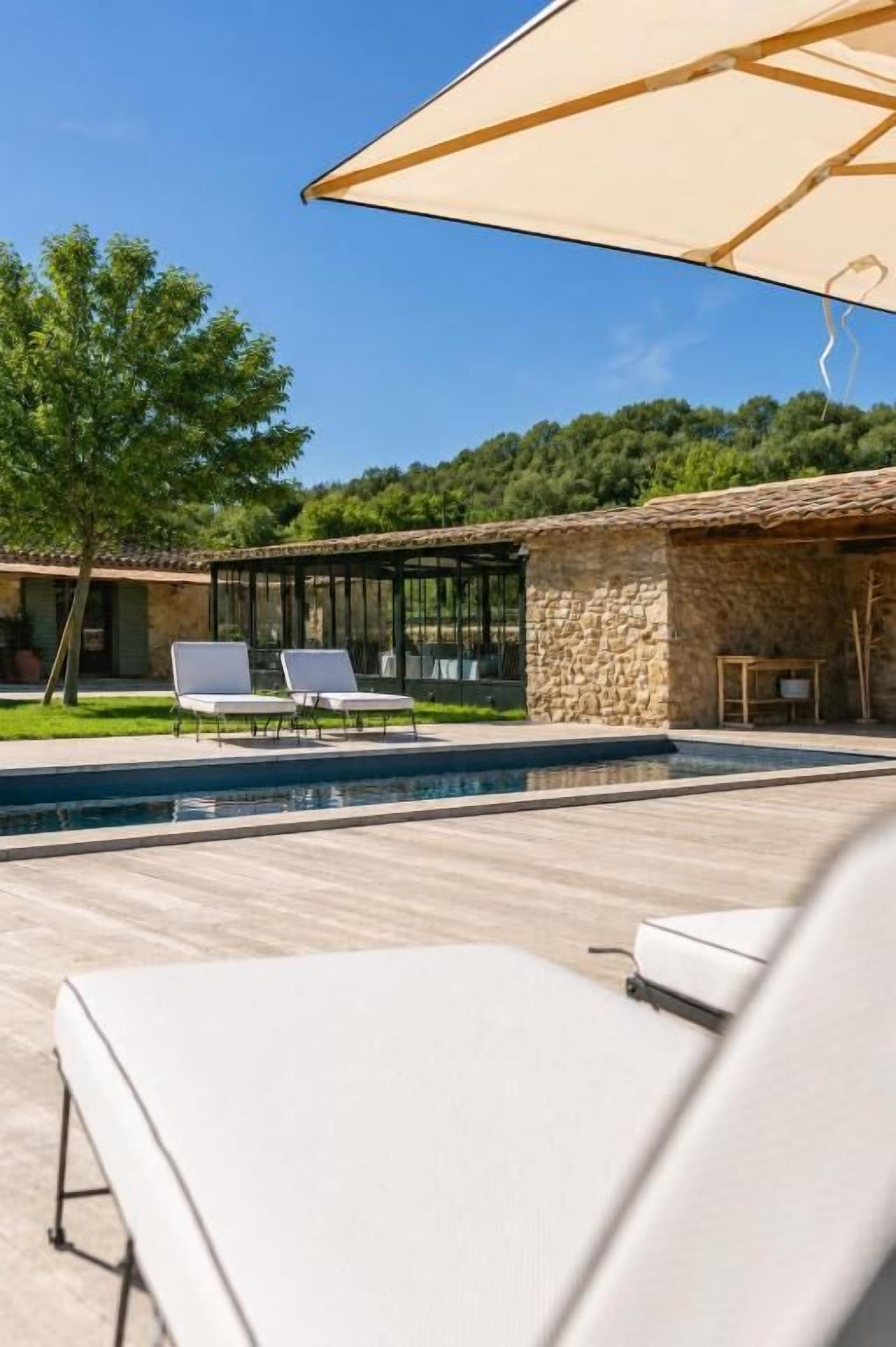 A poolside area with lounge chairs, a stone building, and a clear sky.