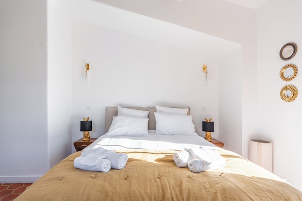 A hotel room with a bed, two bedside tables, a lamp, and a wall-mounted mirror.