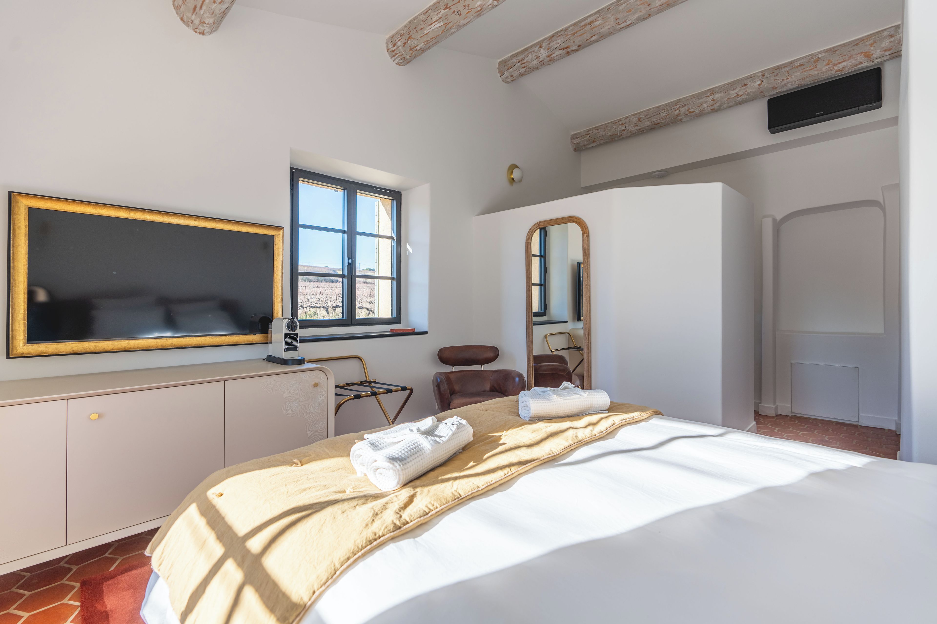 A hotel room with a bed, a large mirror, a window, and a wardrobe.