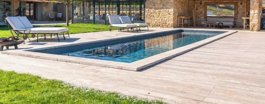Une piscine rectangulaire avec des chaises longues et une terrasse en bois.