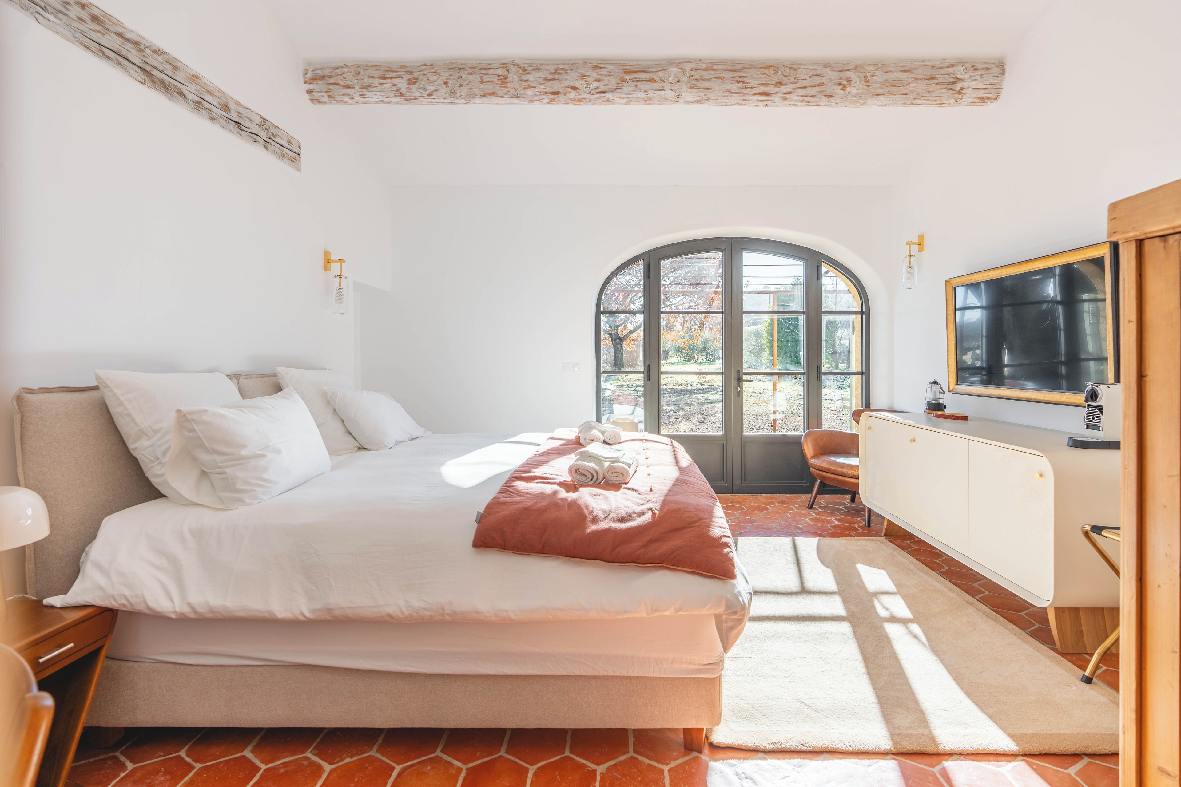 Un dormitorio con cama, ventana, silla y radiador.