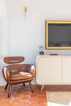 A room with a brown leather chair, a white cabinet with a blackboard, and a tiled floor.