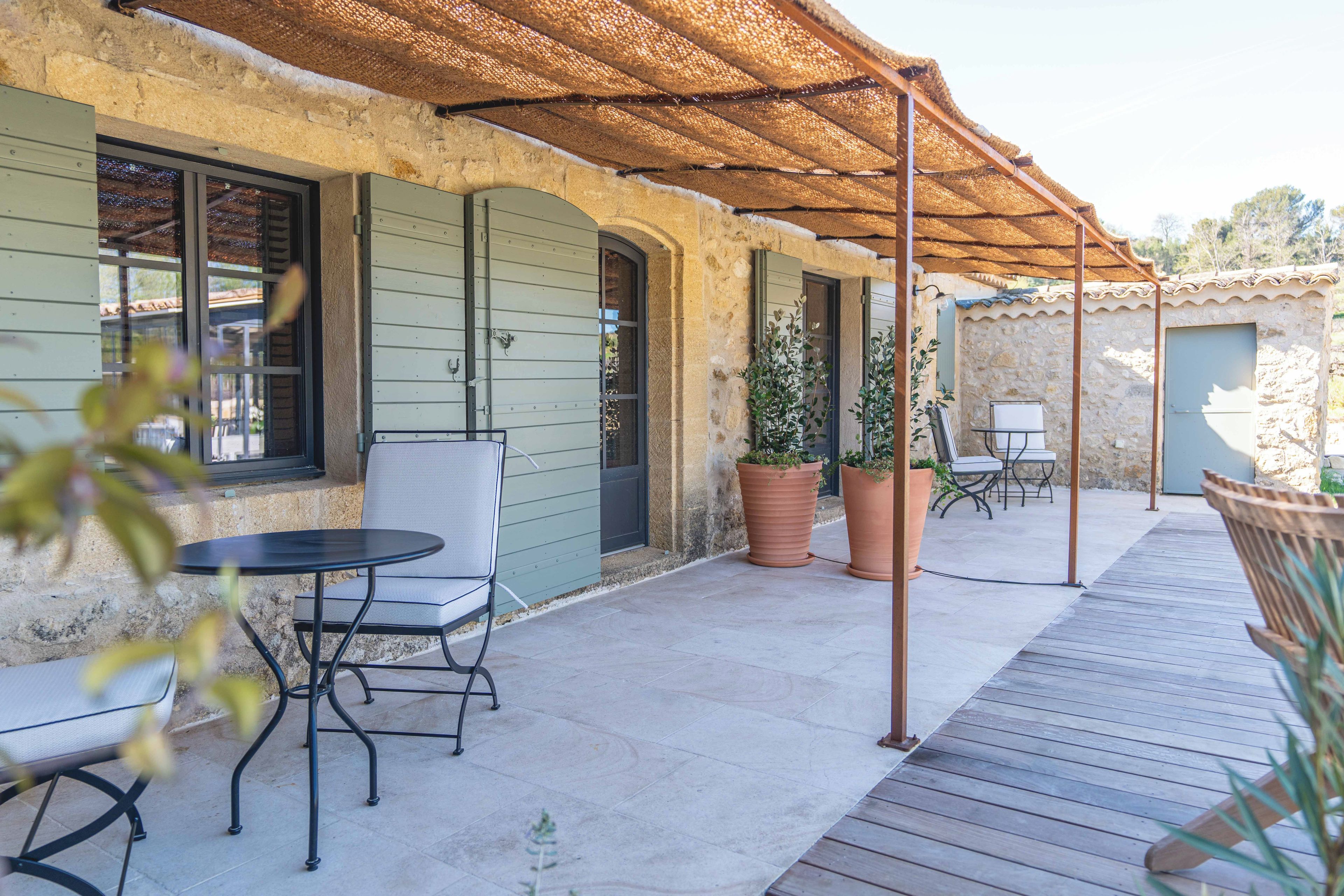 Un espace extérieur aménagé avec une table et des chaises, une pergola et des plantes en pot.