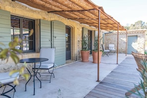 A patio area with a table and chairs, a pergola, and potted plants.