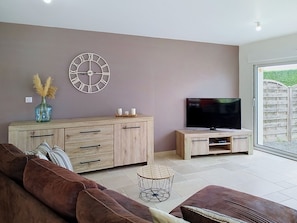 Ein modernes Wohnzimmer mit Sofa, TV-Möbel und Dekorationselementen.