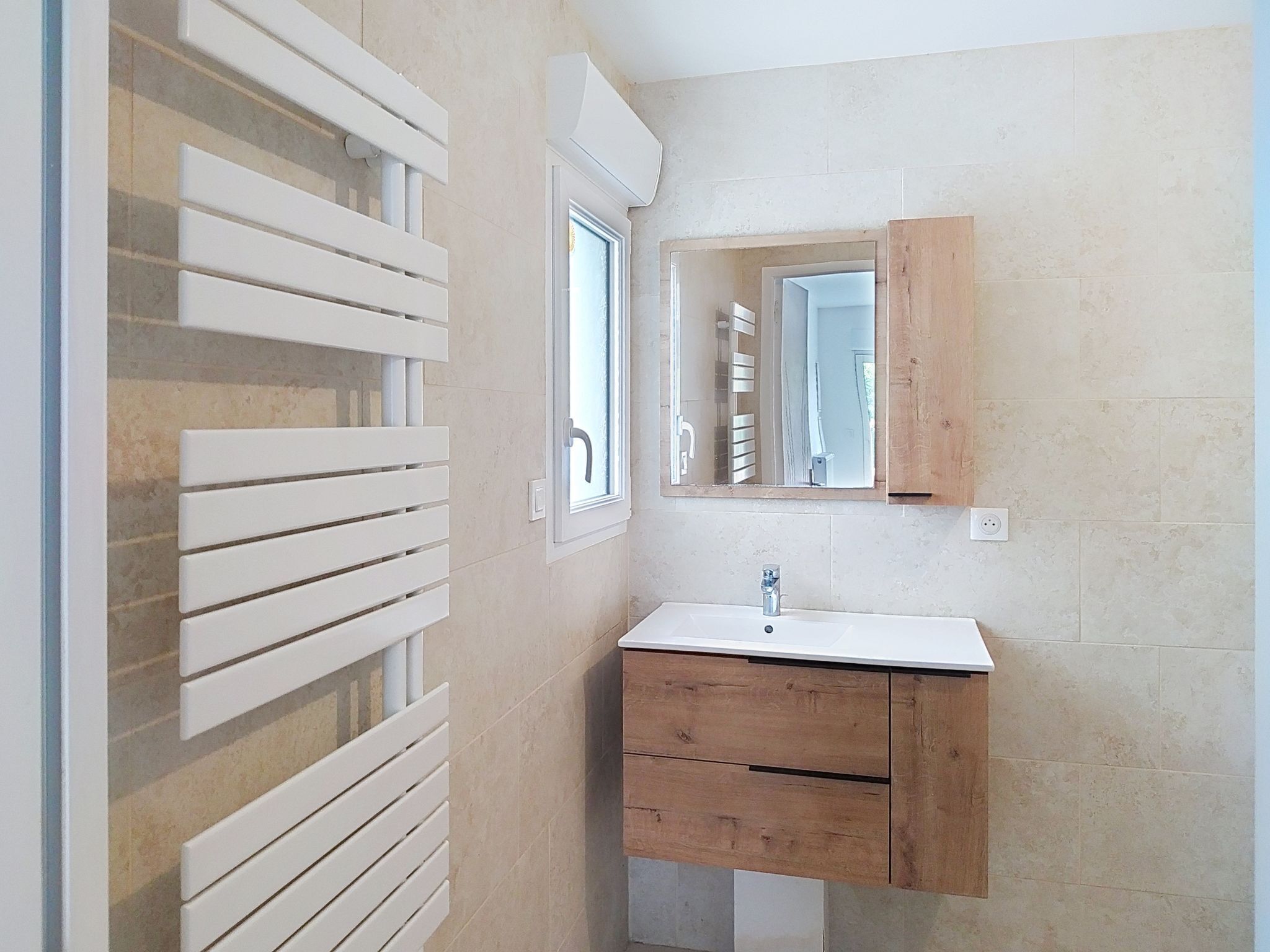 Une salle de bain avec un lavabo blanc, un meuble-lavabo en bois et un miroir.