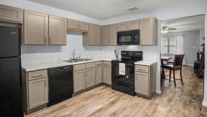 Une cuisine moderne avec des meubles de couleur beige, un réfrigérateur noir, un four à micro-ondes et un lave-vaisselle.