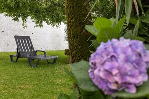 A black outdoor chair on a grassy area with a white wall in the background. - GuestReady - Casa Bela Vista (Ponta Garça)