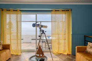 Ein Zimmer mit einem Teleskop auf einem Stativ, einem runden Tisch mit Büchern und zwei Sofas.