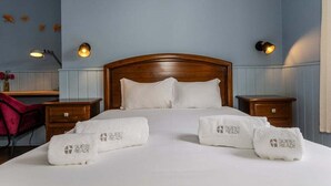 Camera d'albergo con testiera in legno, biancheria da letto bianca e due comodini con lampade.