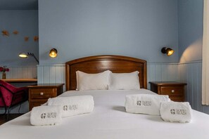 Ein Hotelzimmer mit einem hölzernen Kopfteil, weißer Bettwäsche und zwei Nachttischen mit Lampen.