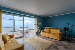 Ein Wohnzimmer mit einer Couch, einem Couchtisch und einem Essbereich mit Stühlen und einem Sonnenschirm.